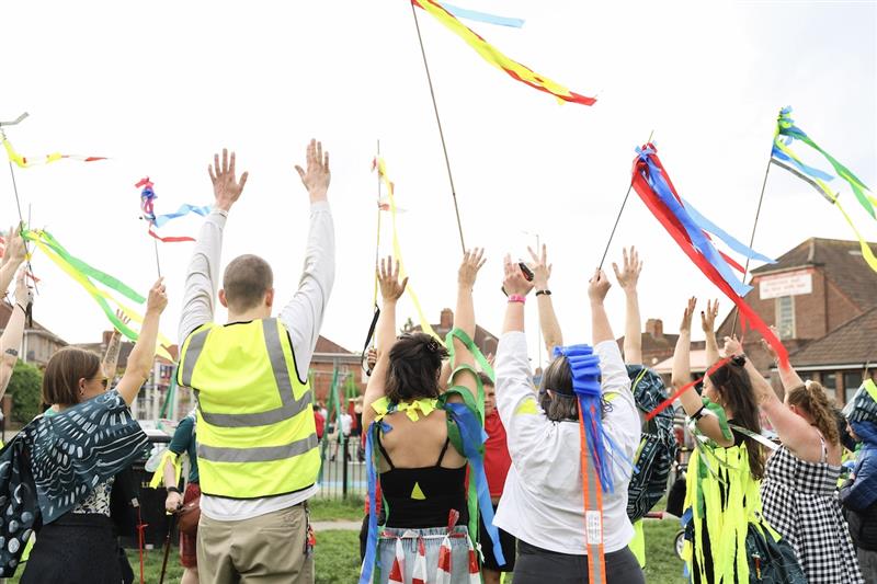 a group of people with their hands in the air. Image is of them from behind.