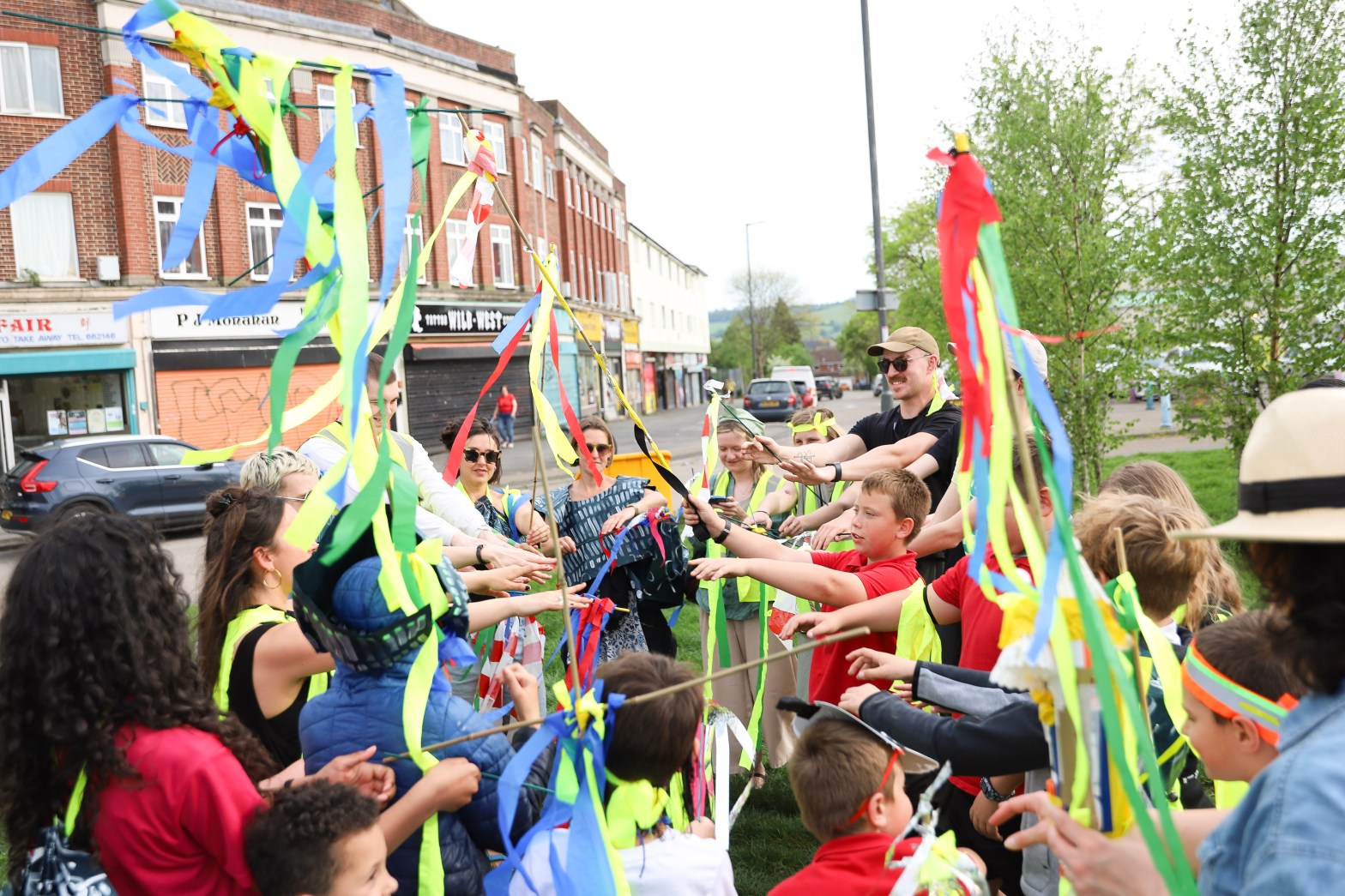 group of people gathered together waving sticks with brightly coloured fabric attached to the sticks