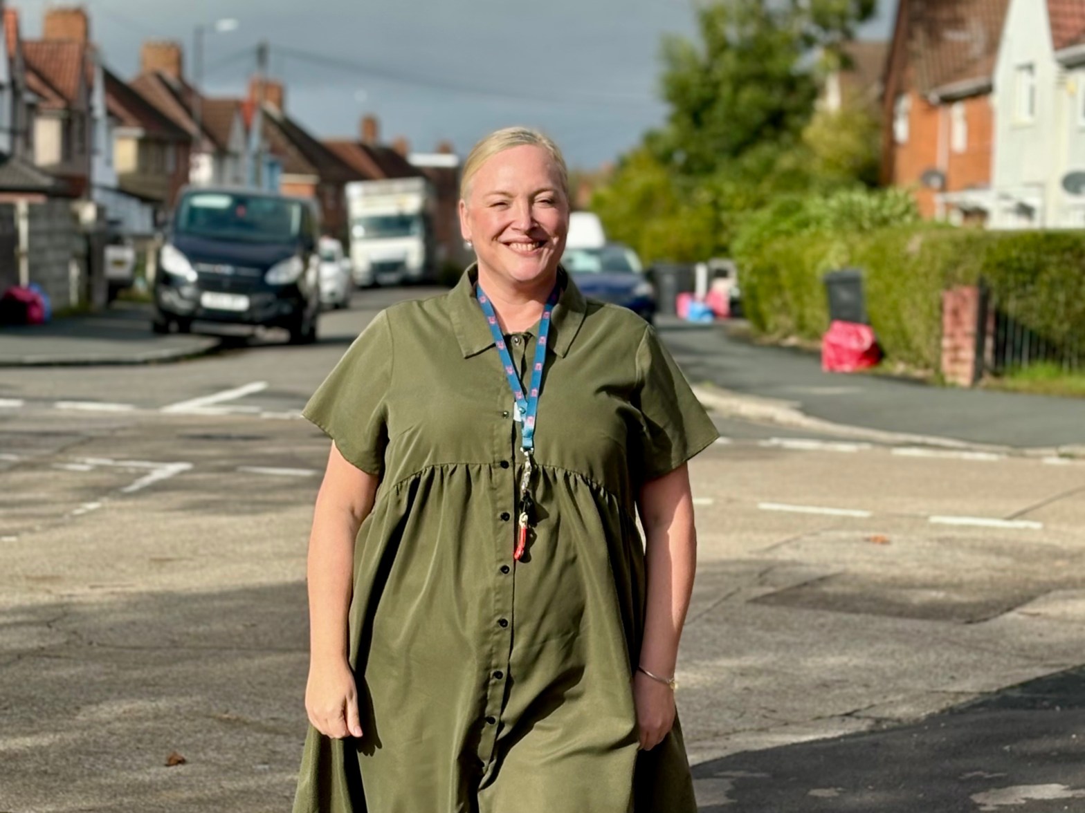 woman with blonde hair wearing green dress standing in the street